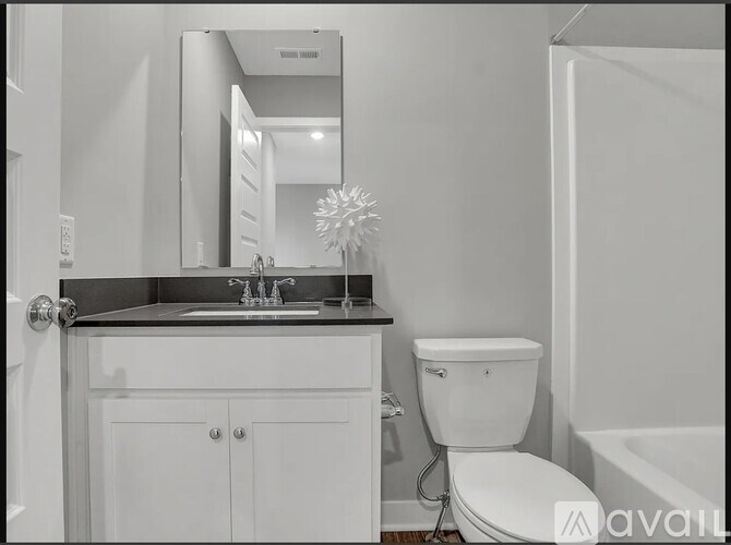 A bathroom with a sink, toilet, and mirror.