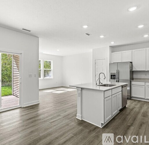 A modern kitchen with white cabinets and a wooden floor.