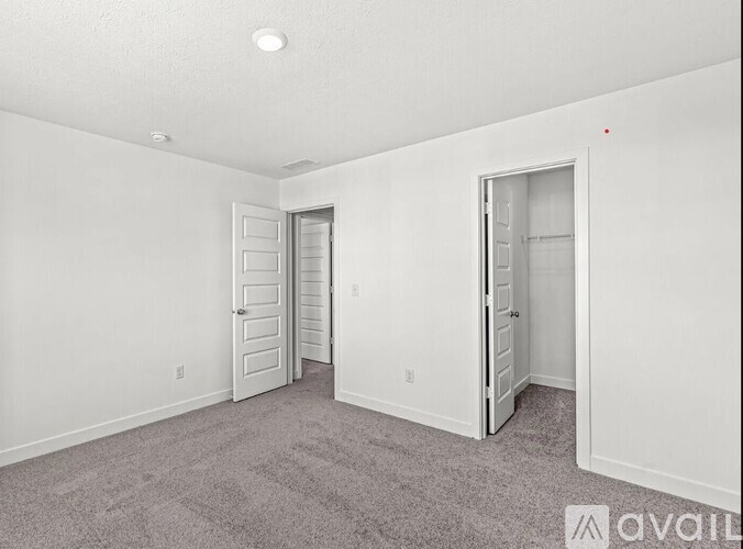 A room with carpeted floor and three doors.