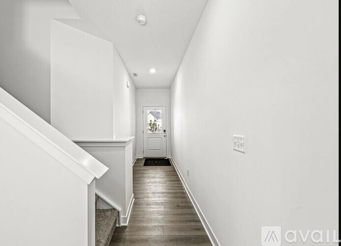 A long hallway with a white door at the end.