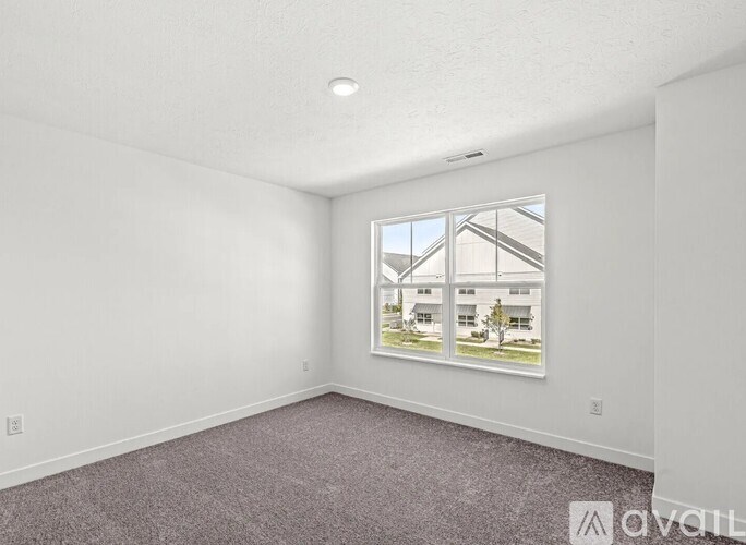 A room with a carpeted floor and a window showing a view of a building.