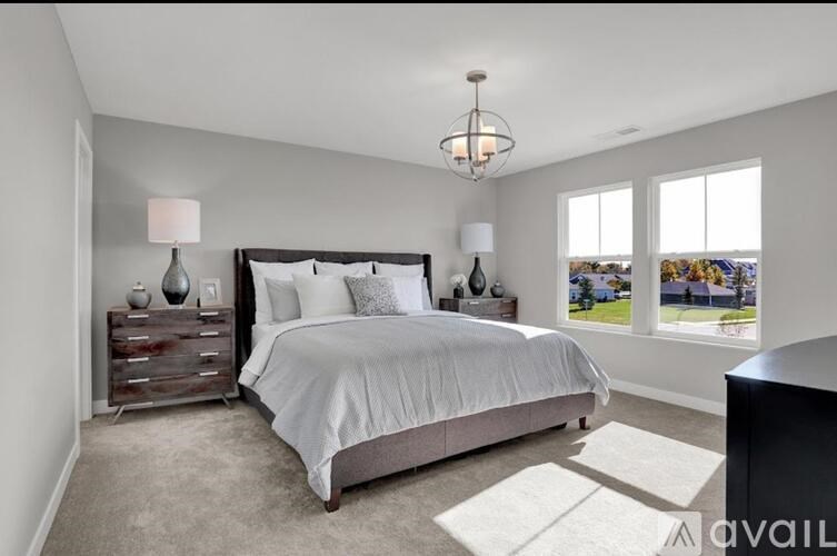 A bedroom with a large bed, a chandelier, and a view of the outdoors through the window.