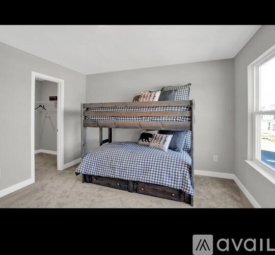 A bedroom with a bunk bed and a window.