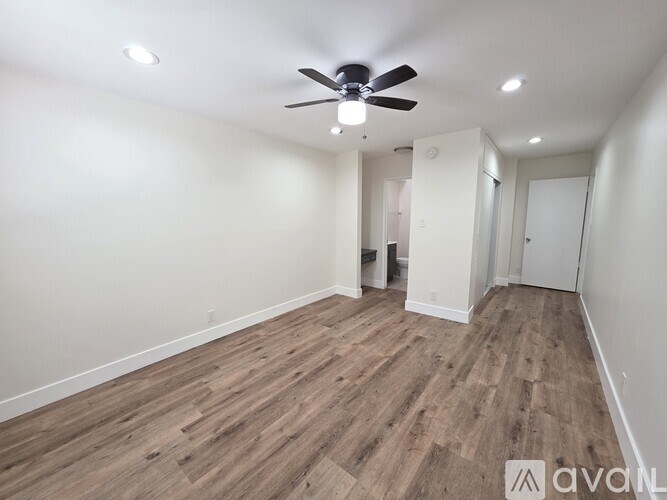 A room with a ceiling fan and wooden flooring.