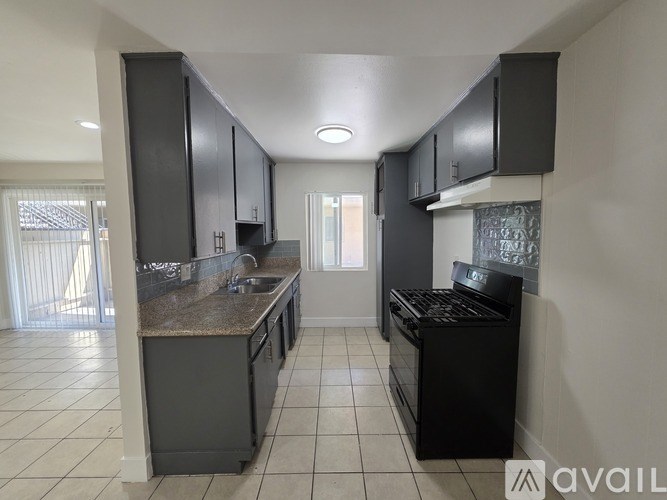 A kitchen with black cabinets and a granite countertop.