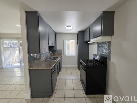 A kitchen with black cabinets and a granite countertop.