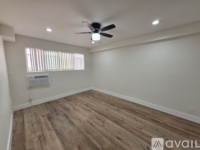 A room with a ceiling fan and wooden flooring.