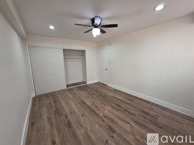 A room with a ceiling fan and wooden flooring.