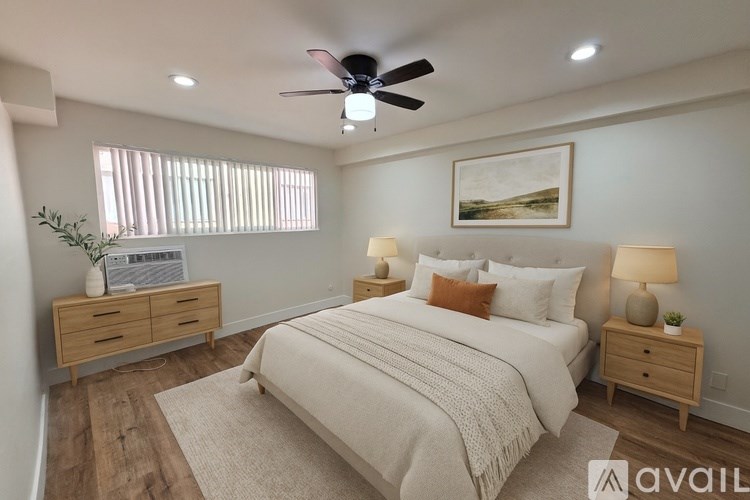 A bedroom with a large bed, a ceiling fan, and a painting on the wall.