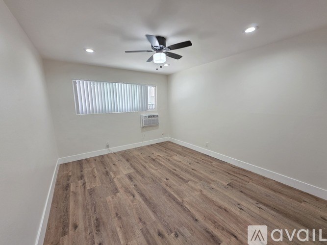 A room with a ceiling fan and wooden flooring.