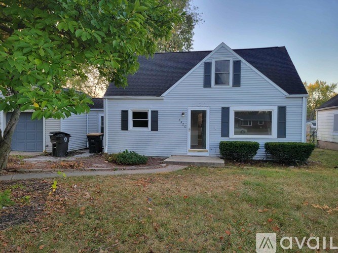 A house with a blue and white exterior is shown with a tree in the foreground.