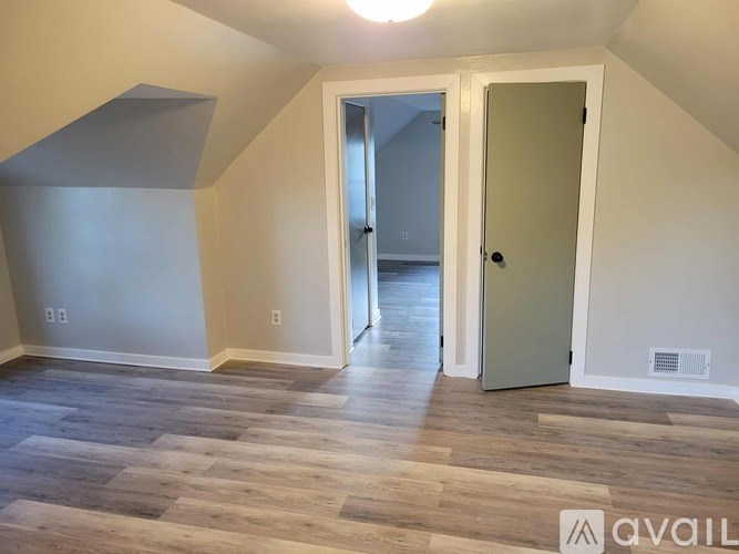 A room with a wooden floor and a door leading to another room.