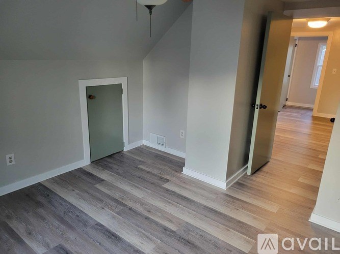 A room with wooden flooring and a doorway leading to another room.