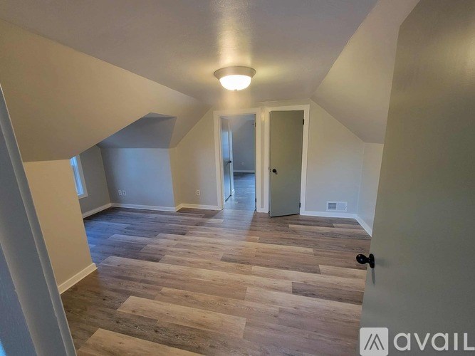 A room with wooden flooring and a doorway leading to another room.