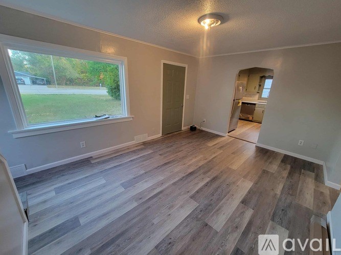 A room with wooden flooring and a window overlooking a green area.