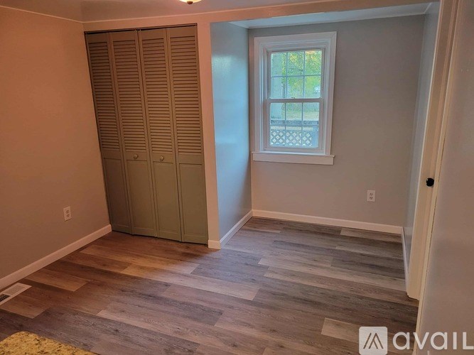 A room with a window and a wooden floor.
