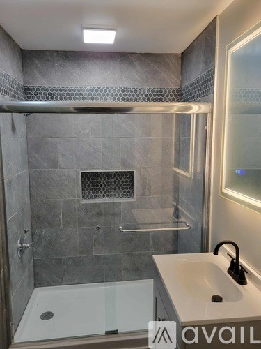 A modern bathroom with a walk-in shower and a white sink.