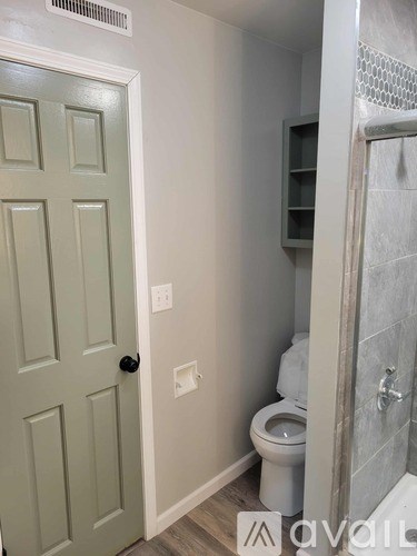 A white toilet sits in a bathroom next to a door.