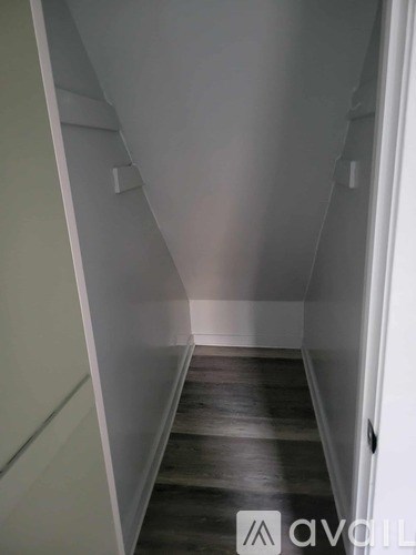 A hallway with wooden floors and white walls.