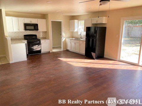 A kitchen with a black refrigerator and white cabinets.
