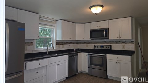 A kitchen with white cabinets and black countertops.