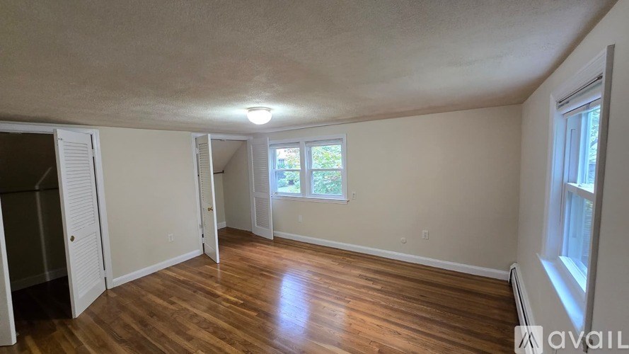 A room with wooden floors and a window letting in natural light.