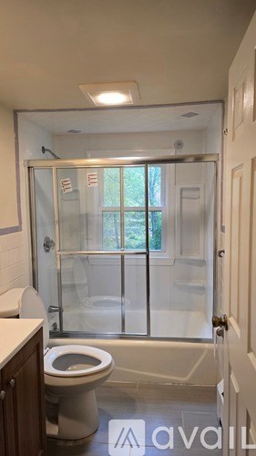 A bathroom with a toilet, sink, and a glass shower door.