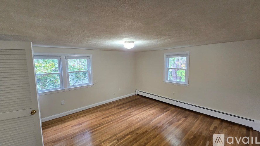 A room with wooden floors and two windows.