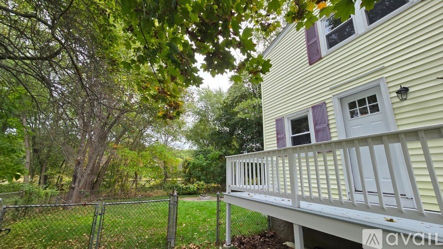 A house with a porch and a fence in front of it.
