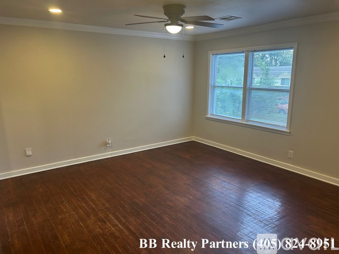 A room with a ceiling fan and a window with blinds.