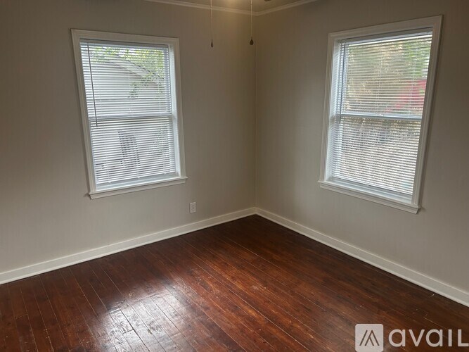 A room with wooden floors and two windows.