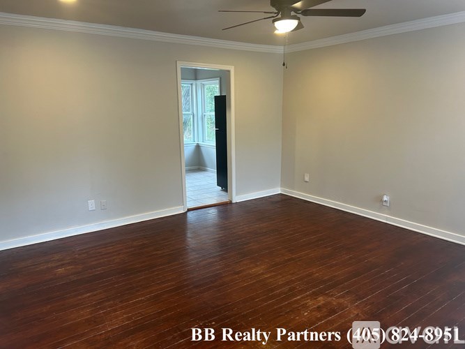 A room with a ceiling fan and wooden flooring.