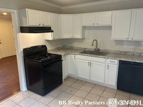 A kitchen with black appliances and white cabinets.