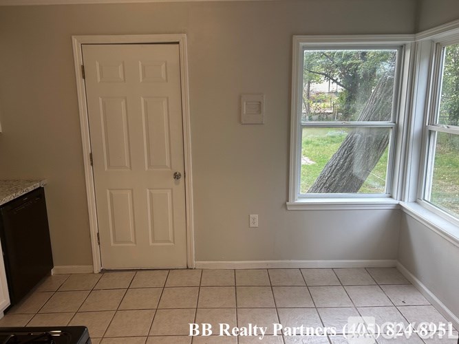 A room with a white door and a window showing a tree outside.