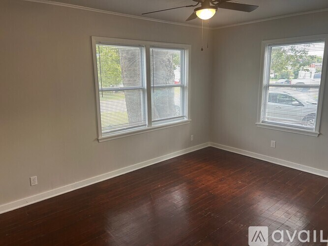 A room with wooden floors and two windows.