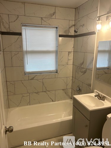 A bathroom with a marble tile wall and a bathtub.