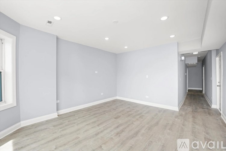 A spacious room with wooden flooring and white walls.