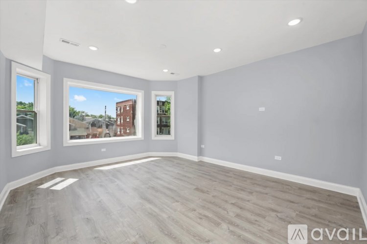 A spacious room with grey walls and a large window showing a view of a red brick building.