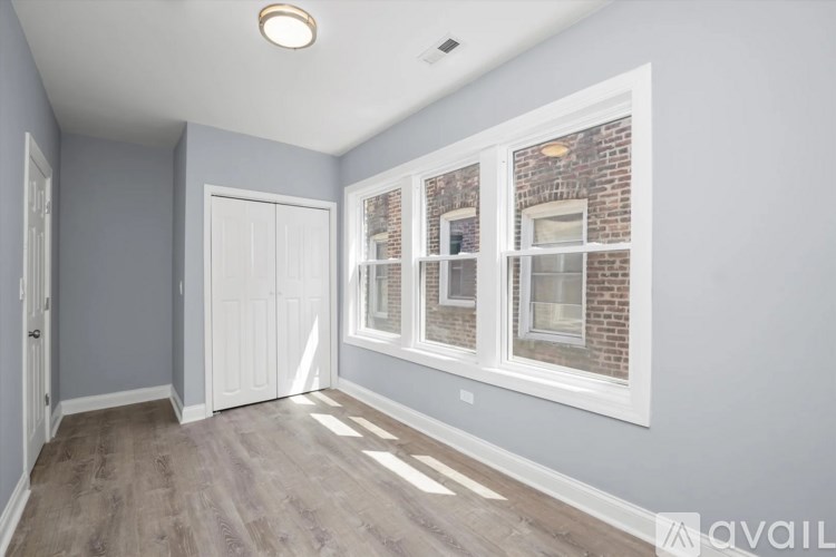 A room with a white door and a window with a brick wall behind it.