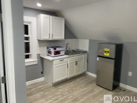 A kitchen with white cabinets and a grey fridge.