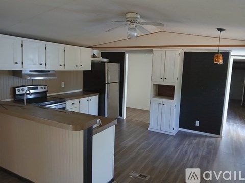 A kitchen with white cabinets and a black refrigerator.
