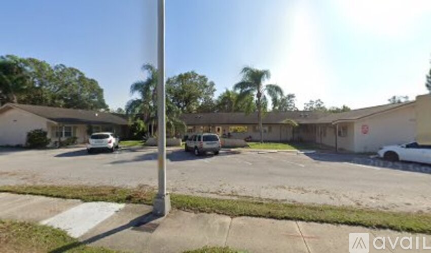 A sunny day in a parking lot with cars and a pole.