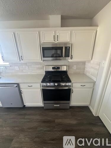 A kitchen with white cabinets and a black stove top oven.