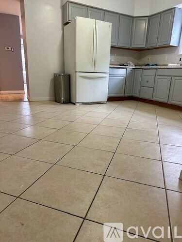 A kitchen with a white fridge and tiled floor.