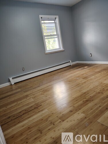 A room with wooden flooring and a window.