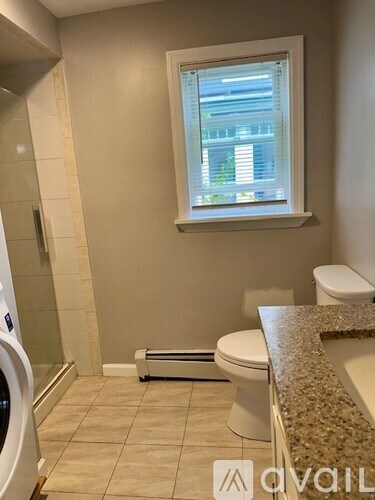A bathroom with a toilet, a window, and a washing machine.
