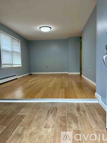 A room with wooden flooring and a window with blinds.