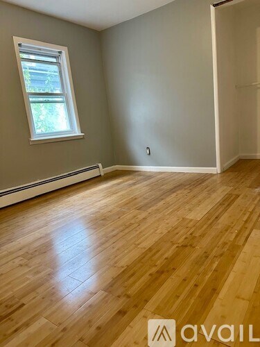 A room with wooden flooring and a window.