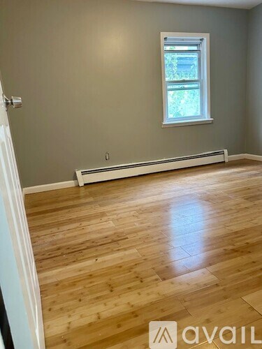 A room with wooden flooring and a window.