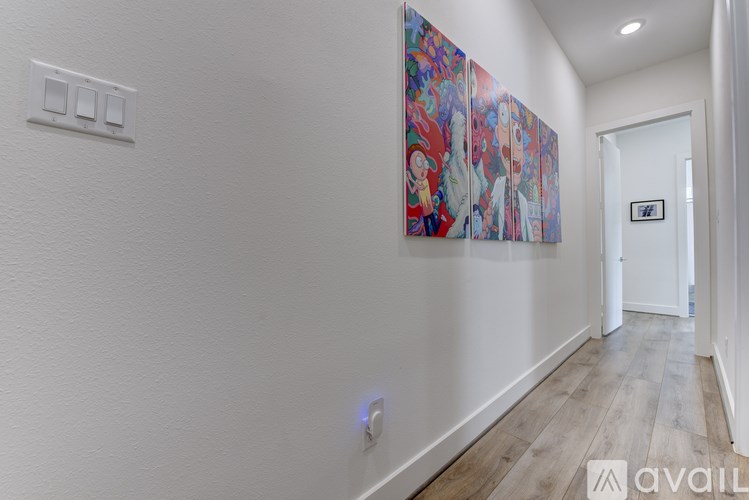 A hallway with a painting on the wall and a door at the end.